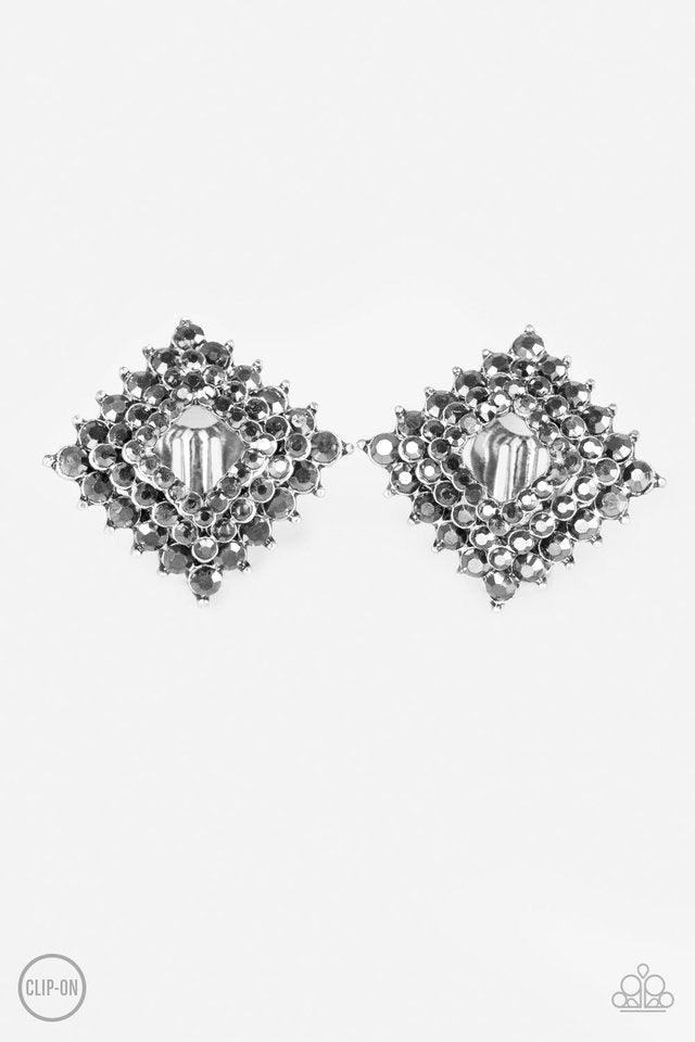 Paparazzi Accessories Kensington Keepsake - Silver *Clip-On Gradually increasing in size, glittery hematite rhinestones are encrusted along three stacking gunmetal frames for a regal look. The square frames slightly curve in towards the ear for an edgy fi