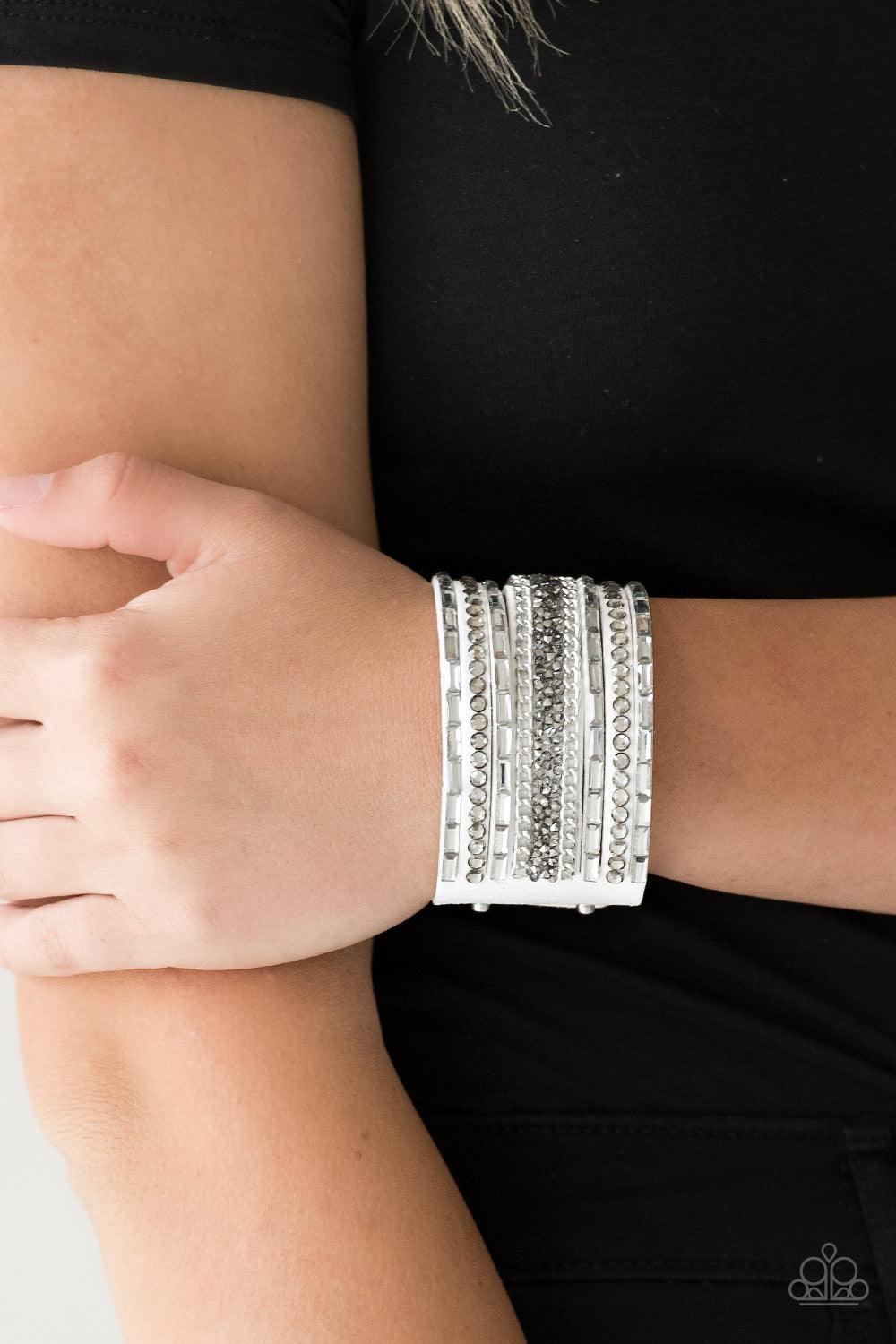 Paparazzi Accessories Rhinestone Rumble - White White emerald-cut rhinestones, smoky round rhinestones, and metallic prism-shaped rhinestones are sprinkled along strands of white suede. Shimmery silver chain is added to the mix for a sassy industrial fini