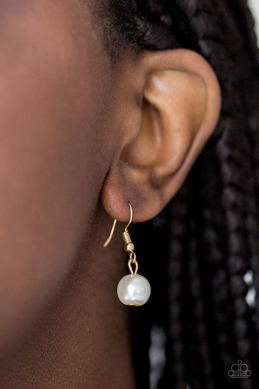Paparazzi Accessories Royal Romance - Gold Gradually increasing in size near the center, a strand of luminescent white pearls falls just below the collar. White rhinestone encrusted rings are sprinkled along the center for a timeless finish. Features an a