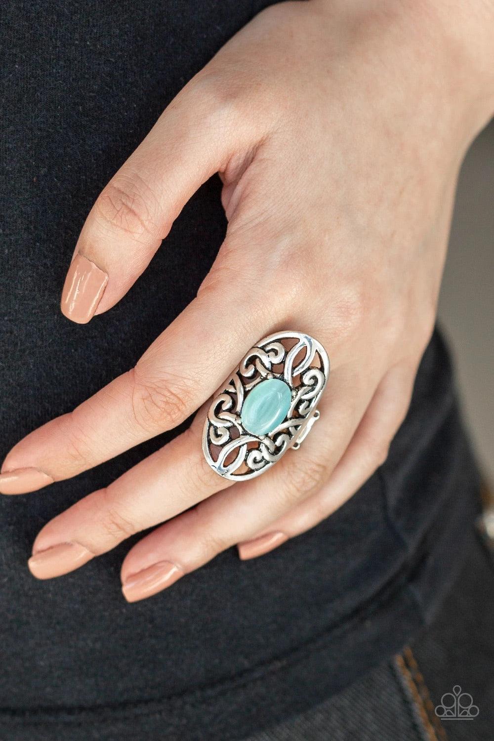 Paparazzi Accessories Gleam Big - Blue A glowing blue cat's eye stone is pressed into the center of an oval backdrop swirling with vine-like filigree for a whimsical look. Features a stretchy band for a flexible fit. Sold as one individual ring. Jewelry