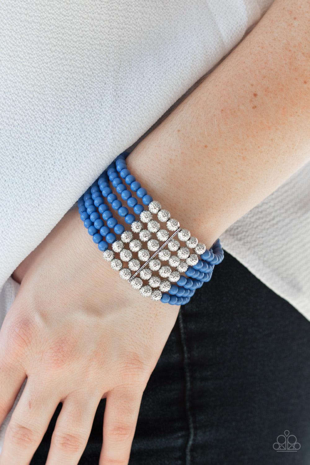 Paparazzi Accessories LAYER It On Thick - Blue Held together with silver fittings, row after row of ornate silver and polished blue beads are threaded along stretchy bands around the wrist of a colorful fashion. Jewelry