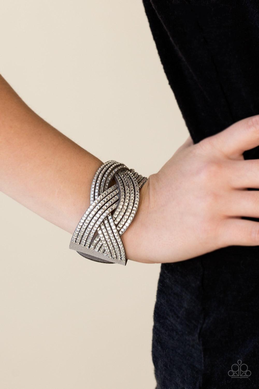 Paparazzi Accessories Big City Shimmer - Silver Glassy white rhinestones are encrusted along crisscrossing strands of gray suede, creating bold shimmer around the wrist. Features an adjustable snap closure. Jewelry