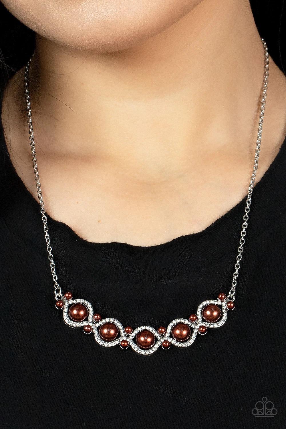 Paparazzi Accessories Life Of The Wedding Party - Brown Enhanced with pairs of dainty brown pearls, white rhinestone encrusted silver bars interweave around bubbly brown pearl-drop centers, creating a refined pendant below the collar. Features an adjustab