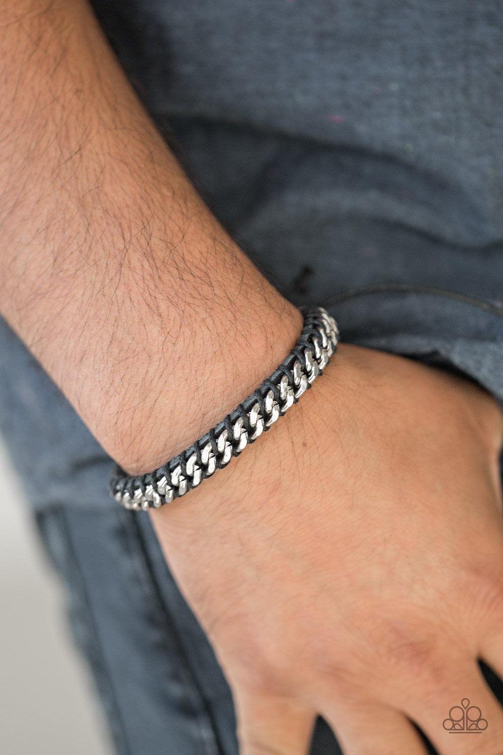 Paparazzi Accessories Rugged Ranger - Black Black cording knots a shimmery silver chain across the front of a black leather band for a rugged look. Features an adjustable sliding knot closure. Jewelry