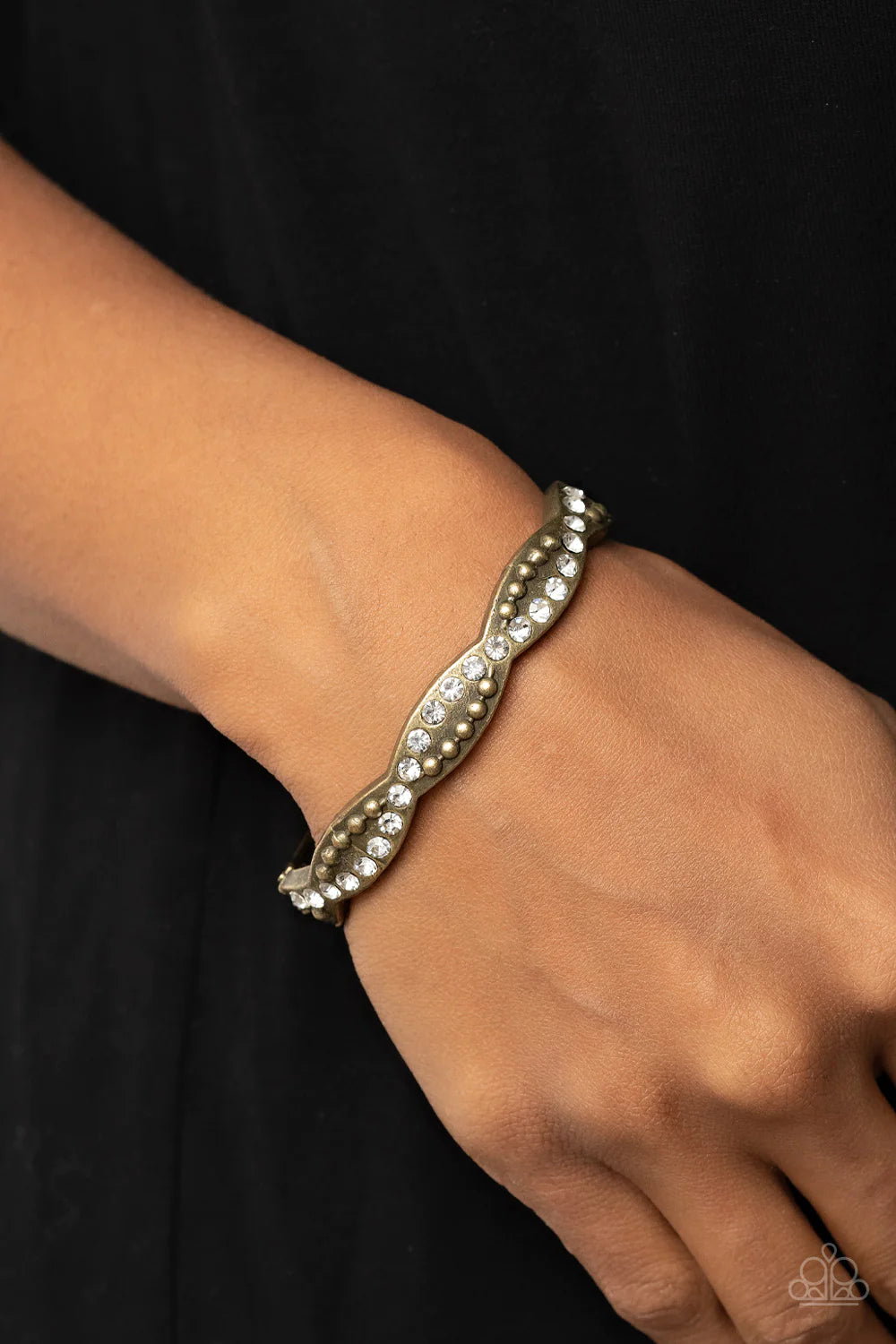 Paparazzi Accessories Empire Envy - Brass Ribbons of antiqued brass studs and glassy white rhinestones delicately intertwines across the front of a scalloped bangle-like bracelet, resulting in an edgy sparkle around the wrist. Jewelry