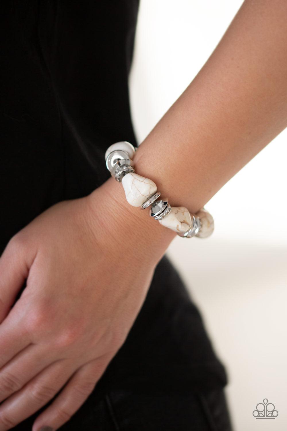 Paparazzi Accessories Stone Age Stunner - White A collection of refreshing white stones, shimmery silver accents, and white rhinestone encrusted rings are threaded along a stretchy band around the wrist for a seasonal look. Sold as one individual bracelet