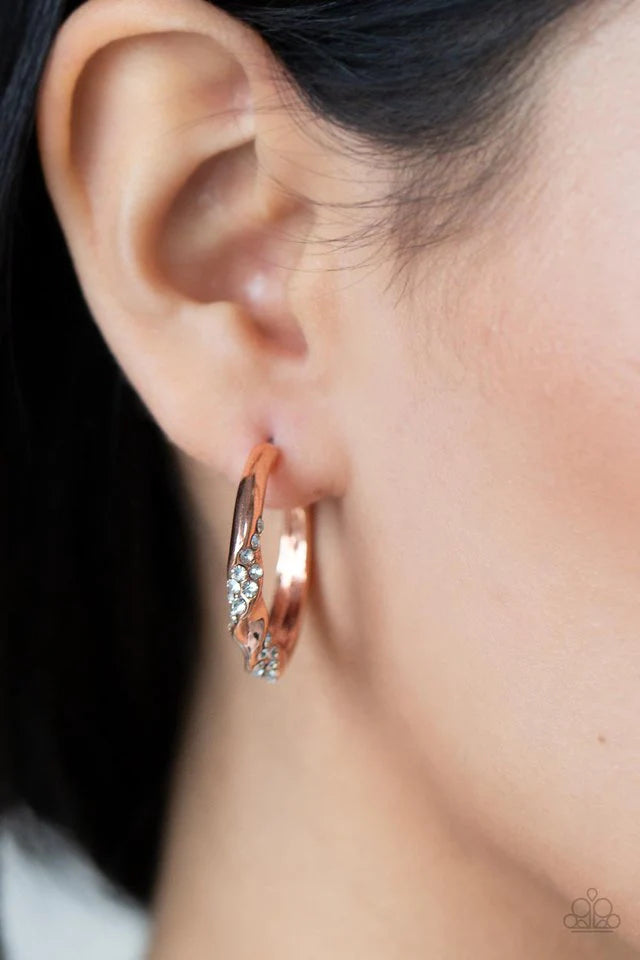 Paparazzi Accessories Subliminal Shimmer - Copper Ribbons of white rhinestones wrap around a dainty shiny copper hoop that has been chiseled and twisted, adding extra dimension. Earring attaches to a standard post fitting. Hoop measures approximately 1" i
