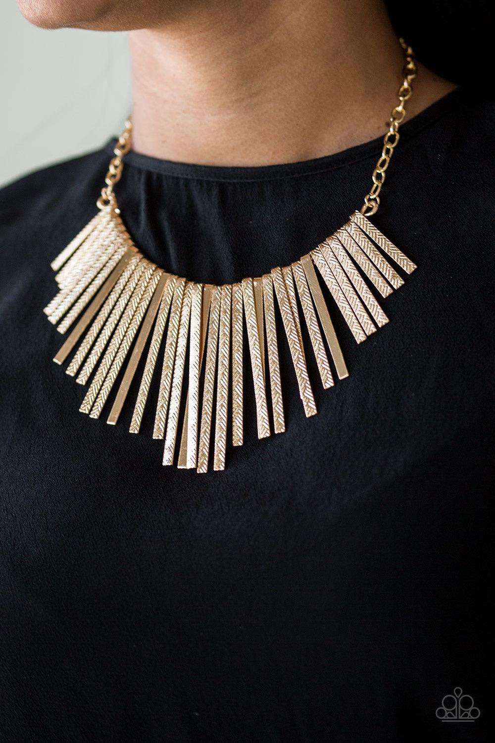 Paparazzi Accessories Welcome To The Pack - Gold Embossed in edgy linear patterns, flat gold rods alternate with plain gold rods below the collar, creating a fiercely tapered fringe. Features an adjustable clasp closure. Jewelry