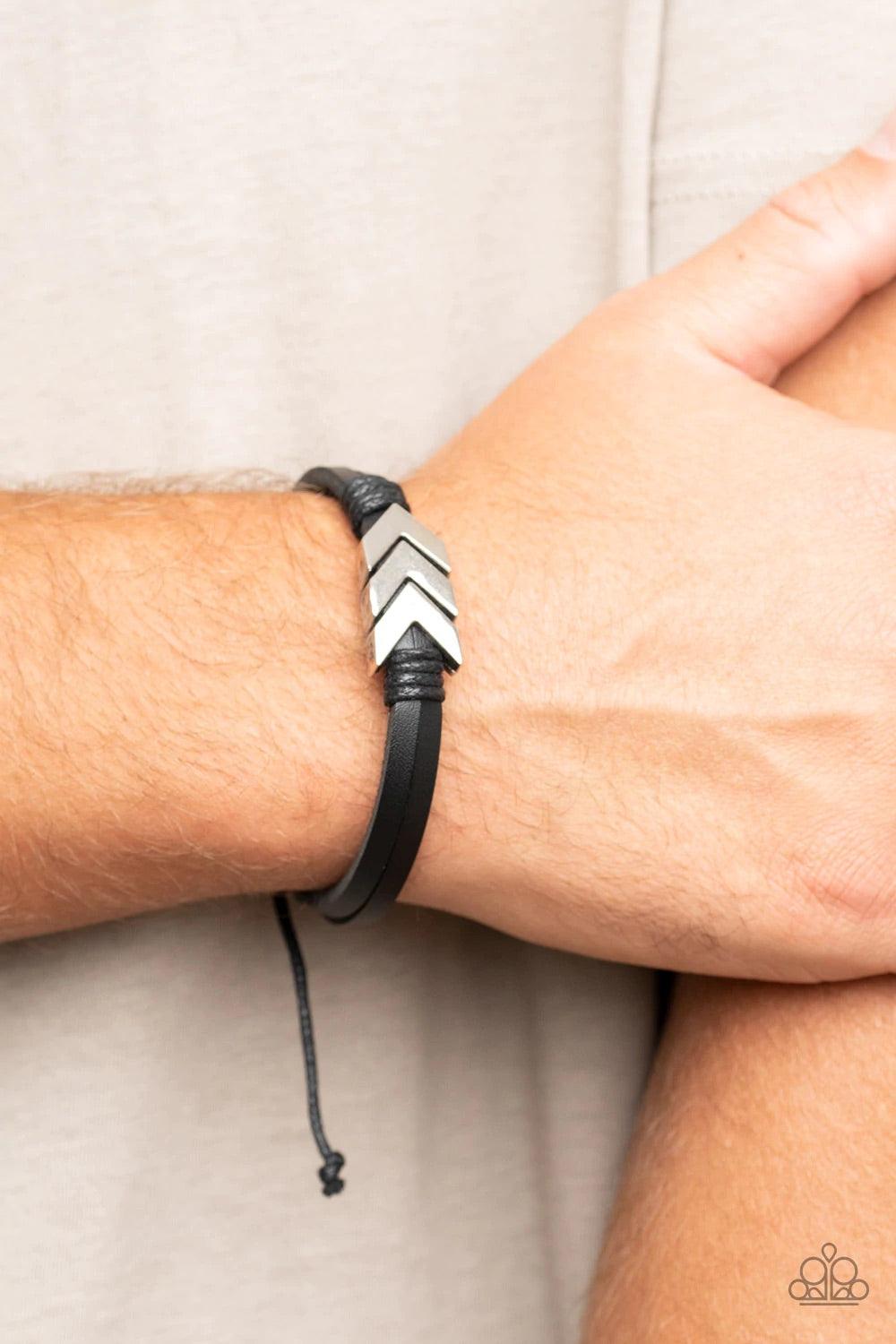Paparazzi Accessories Arrow Pharaoh - Black A rustic silver chevron-like arrow centerpiece is knotted in place along strips of black leather bands, creating an urban statement around the wrist. Features an adjustable sliding knot closure. Sold as one indi