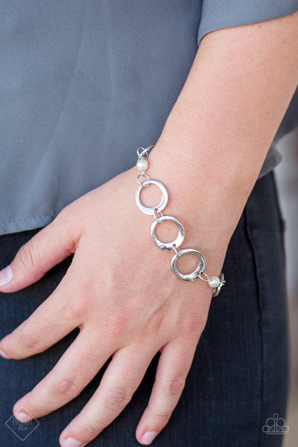Paparazzi Accessories Poised And Polished - White Asymmetrical silver hoops connect with pearly white beads across the wrist for a refined look. Features an adjustable clasp closure. Jewelry