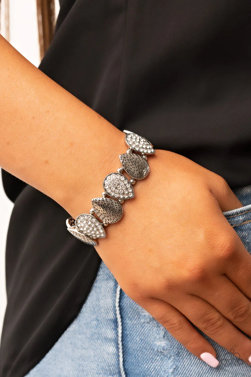 Paparazzi Accessories Playing Favorites - White Infused with pairs of silver beads, a decorative collection of hammered silver teardrops, and white encrusted silver teardrops alternate along stretchy bands around the wrist for an edgy flair. Sold as one i