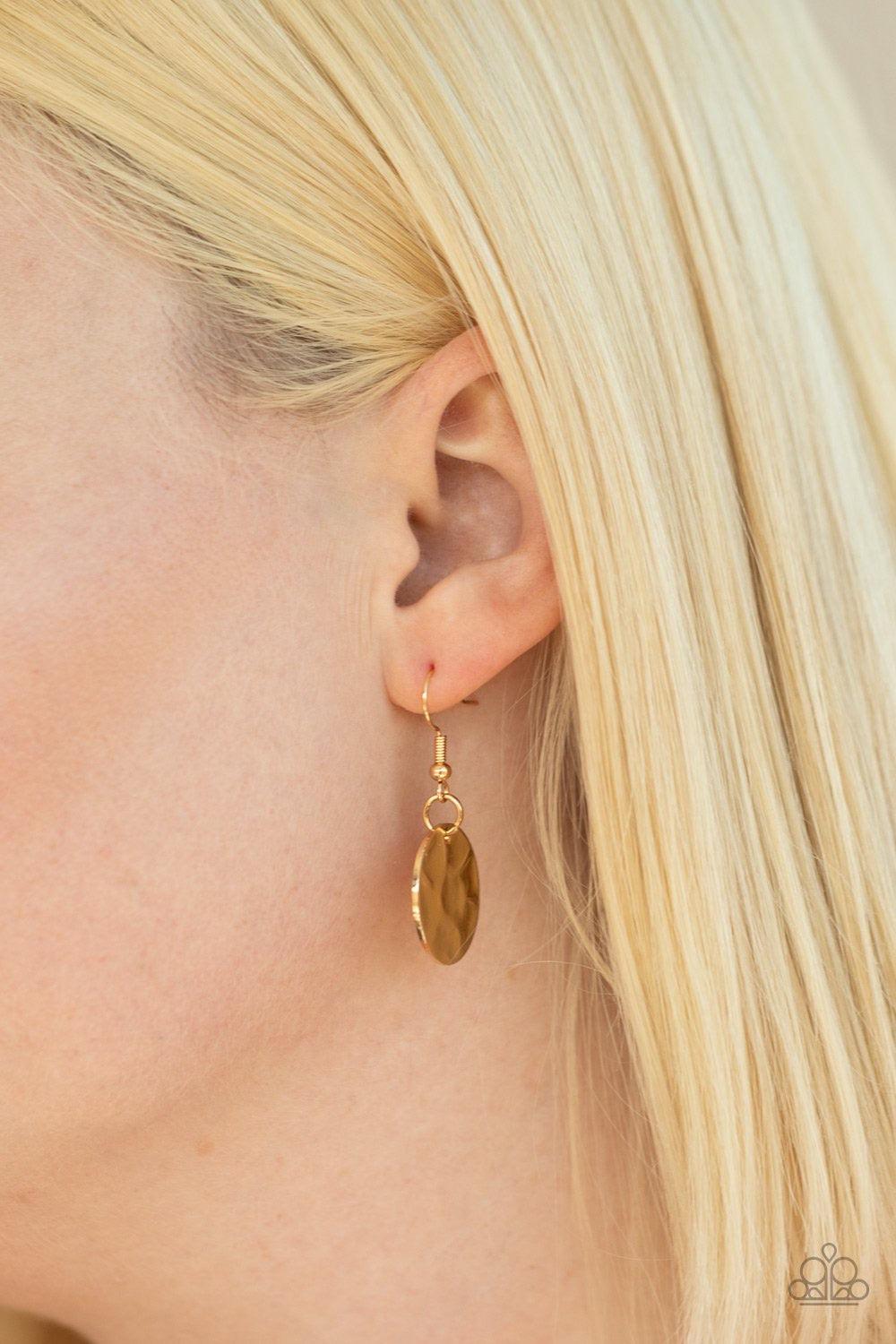 Paparazzi Accessories Trinket Trent ~Gold One row of hammered gold discs and one row of hammered oval links give way to an oversized hammered gold hoop. A collection of gold discs, hammered links, abstract gold pieces, and a shimmery gold chain tassel dan