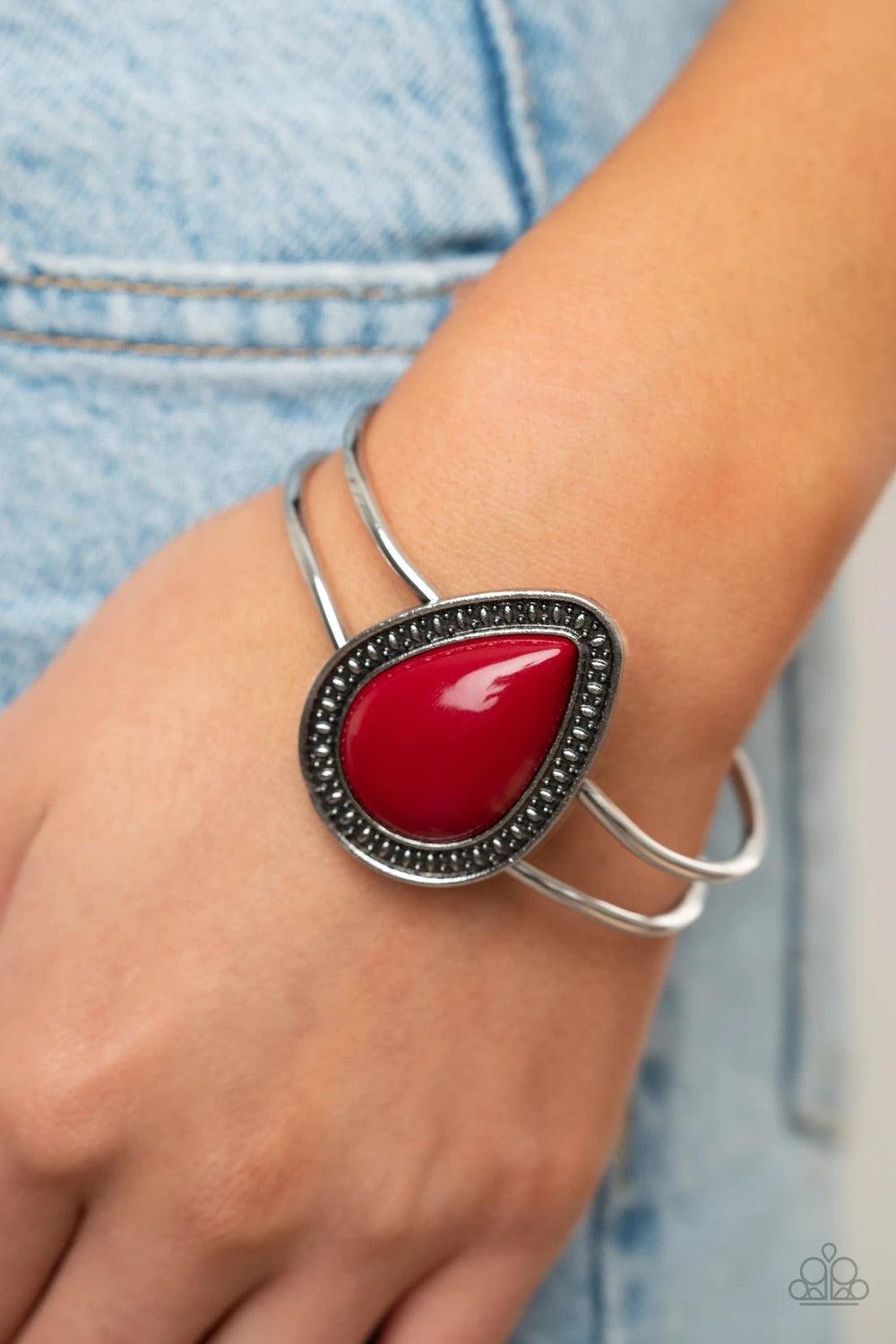 Paparazzi Accessories Over The Top Pop - Red A shiny red teardrop bead is pressed into the center of a studded silver frame atop an airy silver cuff, creating a vibrant pop of color around the wrist. Features a hinged closure. Sold as one individual brace