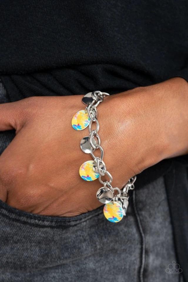 Paparazzi Accessories Teasingly Tie Die - Yellow Featuring a colorful tie dye print, a collection of colorful and dainty silver discs swings from a bulky silver chain around the wrist for a trendy finish. Features an adjustable clasp closure Jewelry