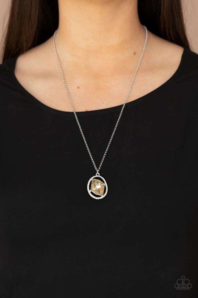 Paparazzi Accessories Undiluted Dazzle - Brown A raw cut topaz gem asymmetrically adorns the center of a warped white rhinestone oval frame, creating an extra sparkly pendant at the bottom of a classic silver frame. Features an adjustable clasp closure. S