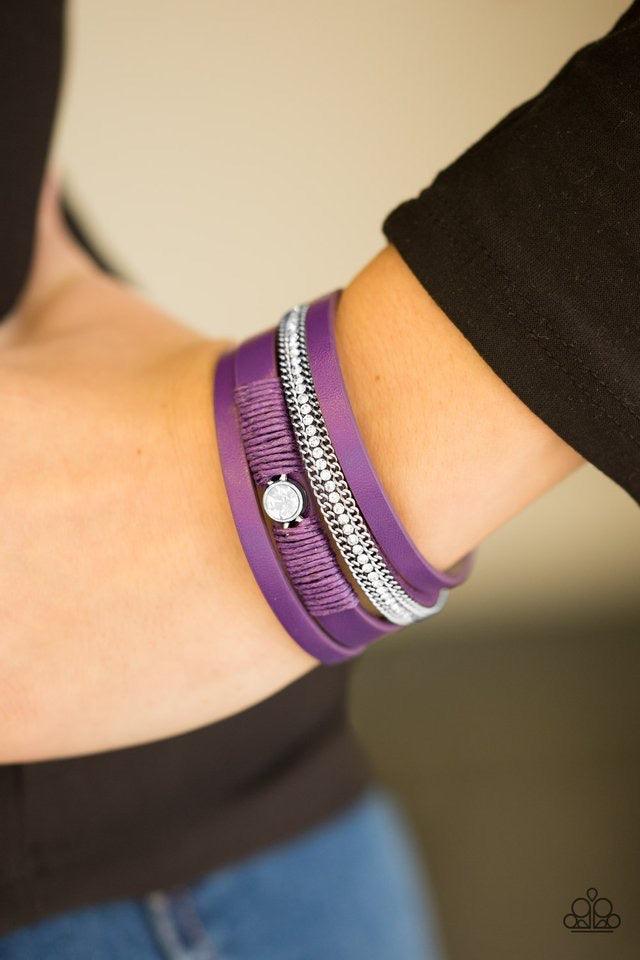 Paparazzi Accessories Catwalk Craze - Purple Vivacious purple leather strands layer across the wrist. Infused with silver chain and white rhinestone accents, purple cording knots around a leather strand, securing a solitaire white rhinestone in place for