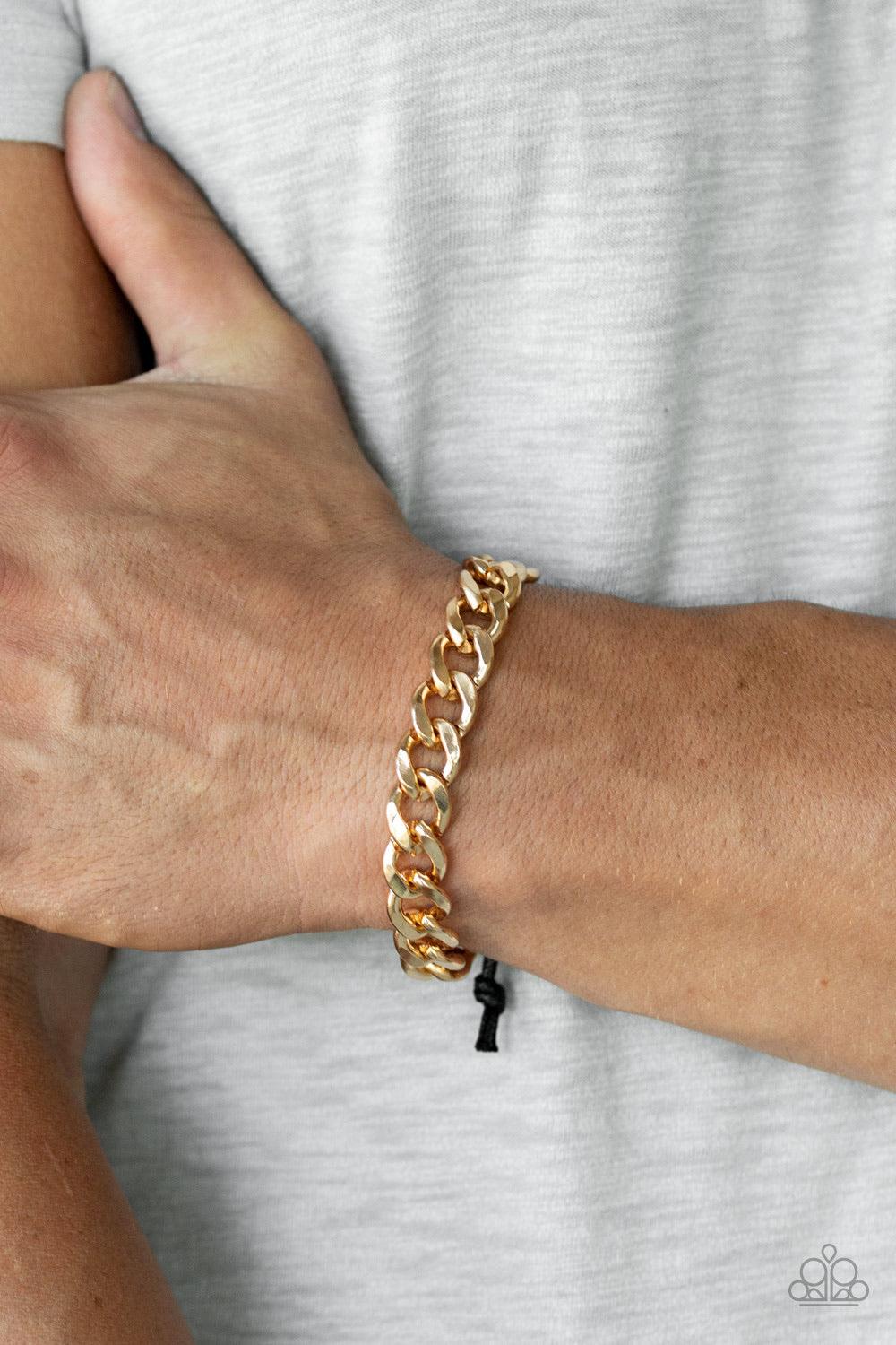 Paparazzi Accessories Renegade - Gold Shiny black cording knots around the ends of a thick gold beveled cable chain that is wrapped across the top of the wrist for a versatile look. Features an adjustable sliding knot closure. Jewelry