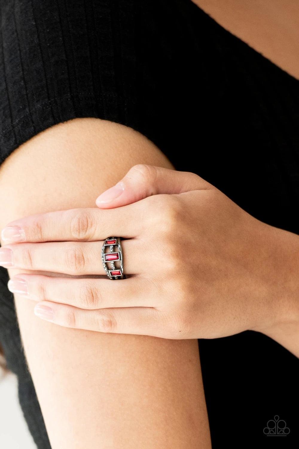 Paparazzi Accessories Noble Nova - Red Three red emerald-cut rhinestones are encrusted along three gunmetal bands radiating with smooth surfaces and sections of glittery hematite rhinestones for an edgy fashion. Features a stretchy band for a flexible fit