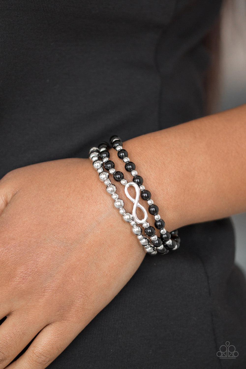 Paparazzi Accessories Immeasurable Infinite - Black Polished black and shiny silver beads are threaded along stretchy bands, creating colorful layers around the wrist. A dainty silver infinity charm adorns one strand for a whimsical finish. Sold as one se