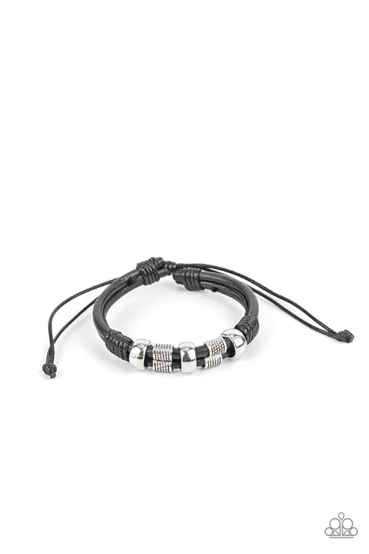 Paparazzi Accessories Urban Cattle Drive - Black Shiny and textured silver cylindrical accents slide along a double layer of thick black leather cording. Glossy thread wrangles the ends together creating a rustic finish as it wraps around the wrist. Featu