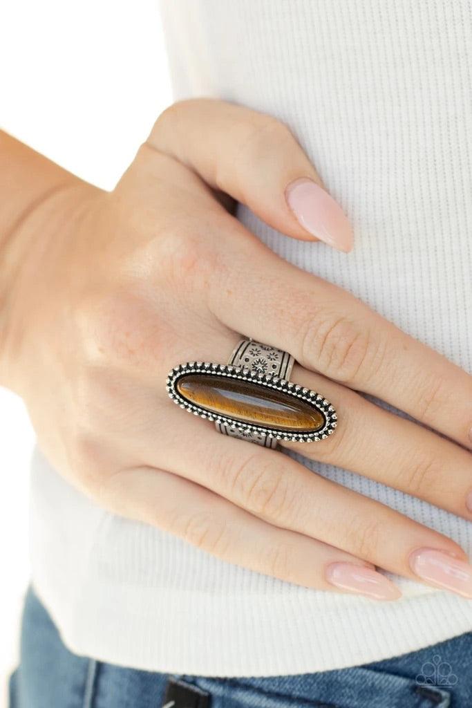 Paparazzi Accessories Ultra Luminary - Brown An oblong tiger's eye stone adorns the center of a studded silver frame that sits atop a thick silver band stamped in antiqued stars. Features a stretchy band for a flexible fit. Sold as one individual ring. Je