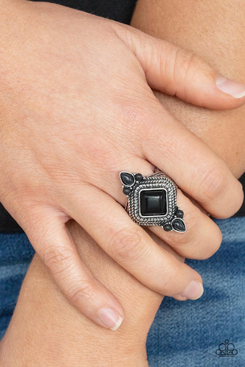 Paparazzi Accessories Mesa Mystic - Black A square black stone tilts inside a stacked silver frame embossed in metallic ropelike textures. Trios of dainty black stones adorn the top and bottom of the frame, adding a trendy flair to the tribal inspired cen