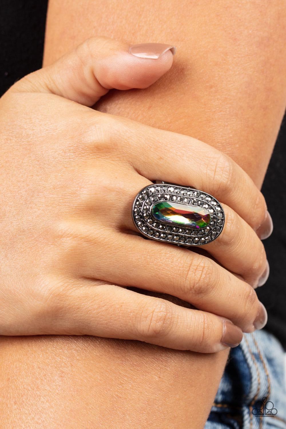 Paparazzi Accessories Fueled by Fashion - Multi An elongated sparkling oil spill gem is nestled inside a linear hematite frame created by double rows of dainty smoky rhinestones. The faceted gem creates a glamorously edgy effect atop the finger. Features