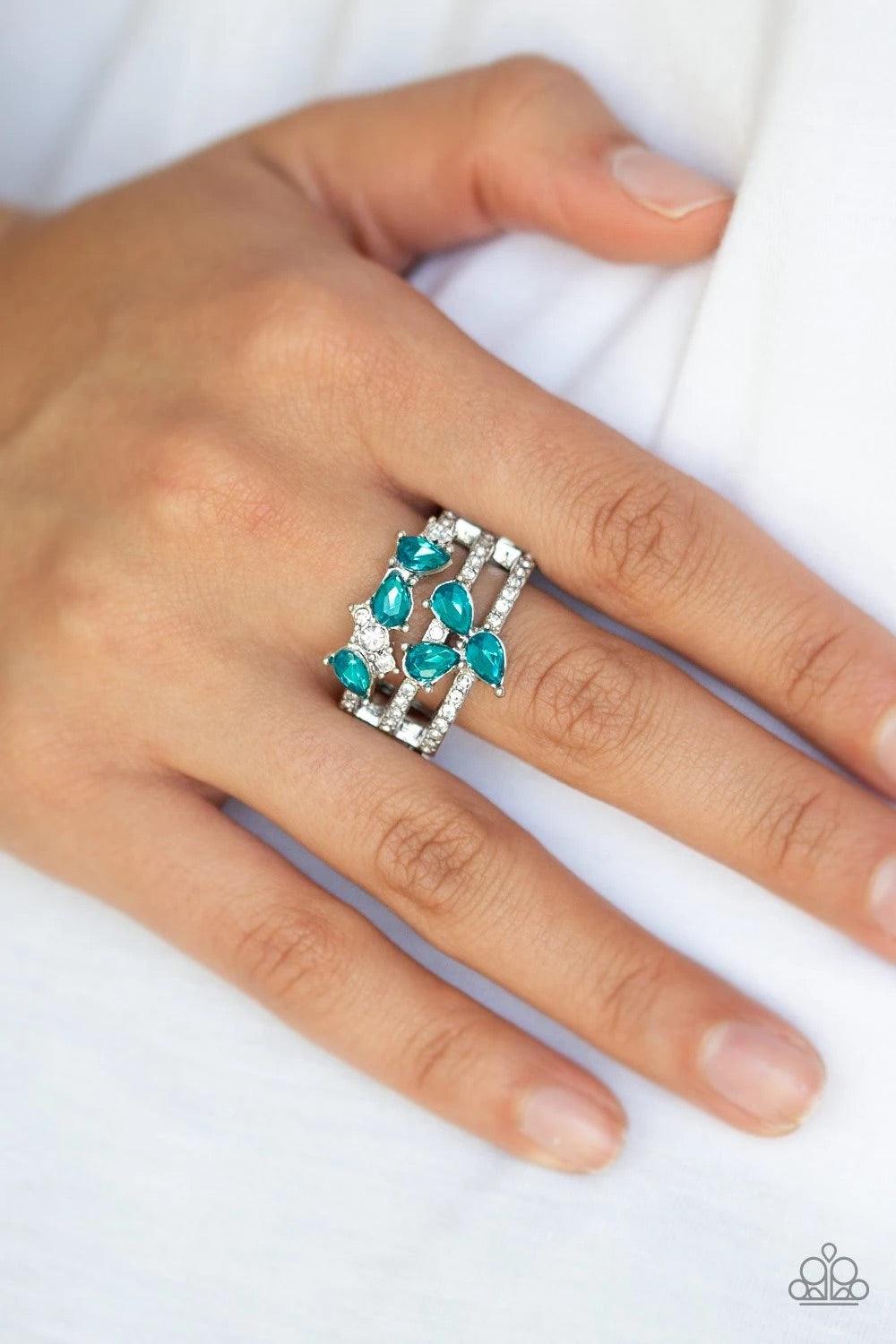 Paparazzi Accessories Blink Back TIERS - Blue Dainty white rhinestones and blue teardrop gems are sprinkled across the center of tiered silver bands encrusted in dazzling white rhinestones. Features a stretchy band for a flexible fit. Sold as one individu