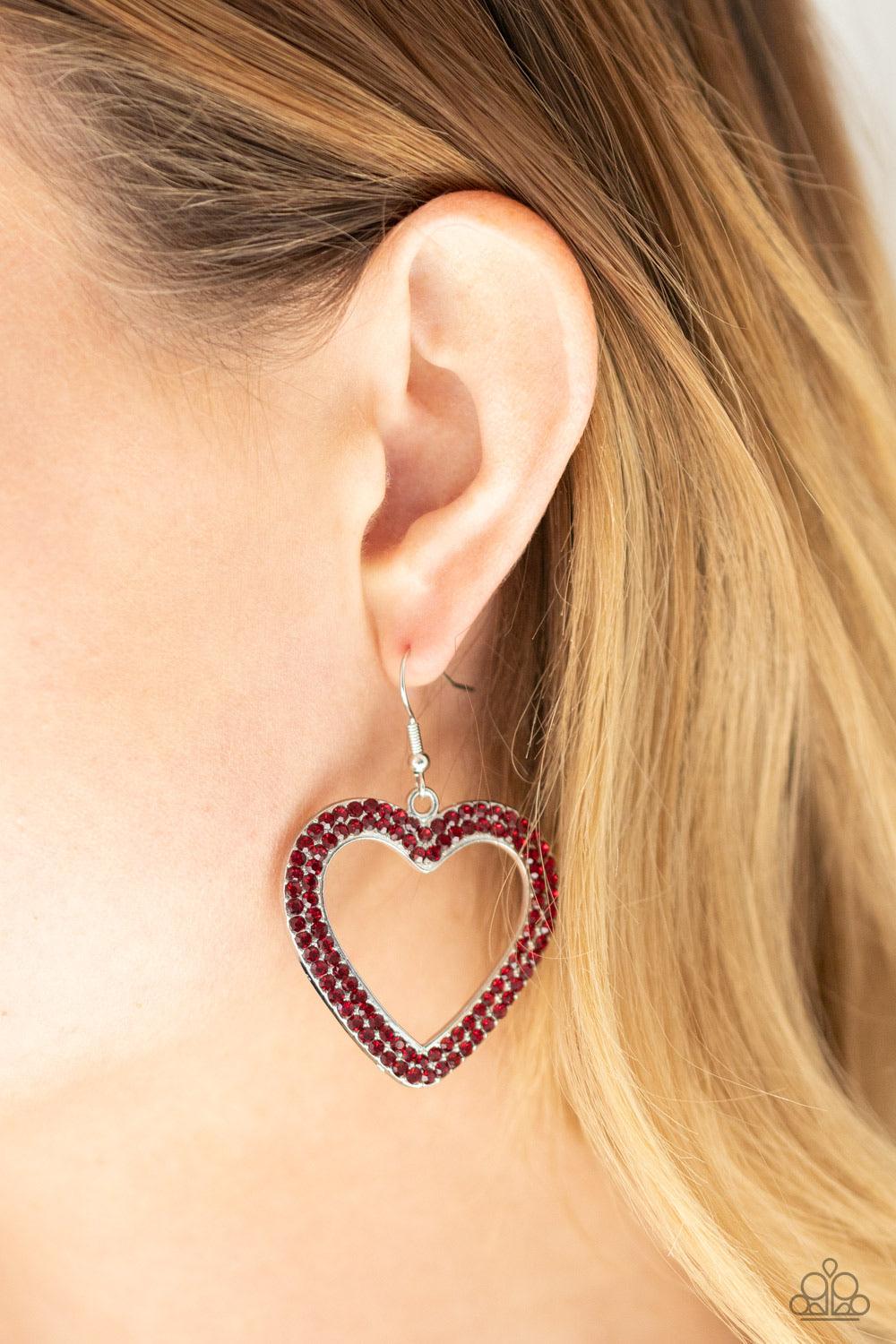 Paparazzi Accessories GLISTEN To your Heart - Red Two rows of fiery red rhinestones are encrusted along the front of a silver heart frame, creating a flirty centerpiece. Earring attaches to a standard fishhook fitting. Sold as one pair of earrings. Jewelr