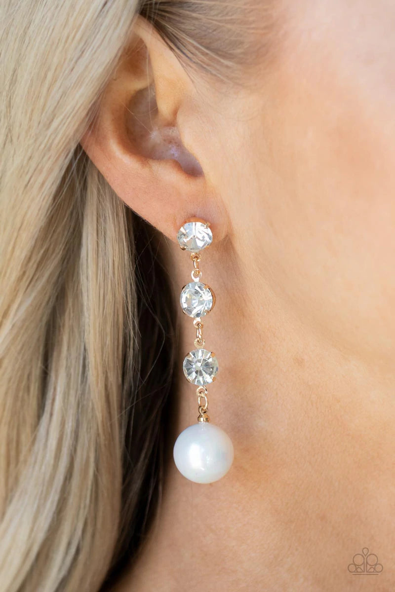 Paparazzi Accessories Yacht Scene - Gold Encased in sleek gold fittings, a trio of classic white rhinestones give way to an oversized iridescent pearl, creating an elegantly extended chandelier. Earring attaches to a standard post fitting. Sold as one pai