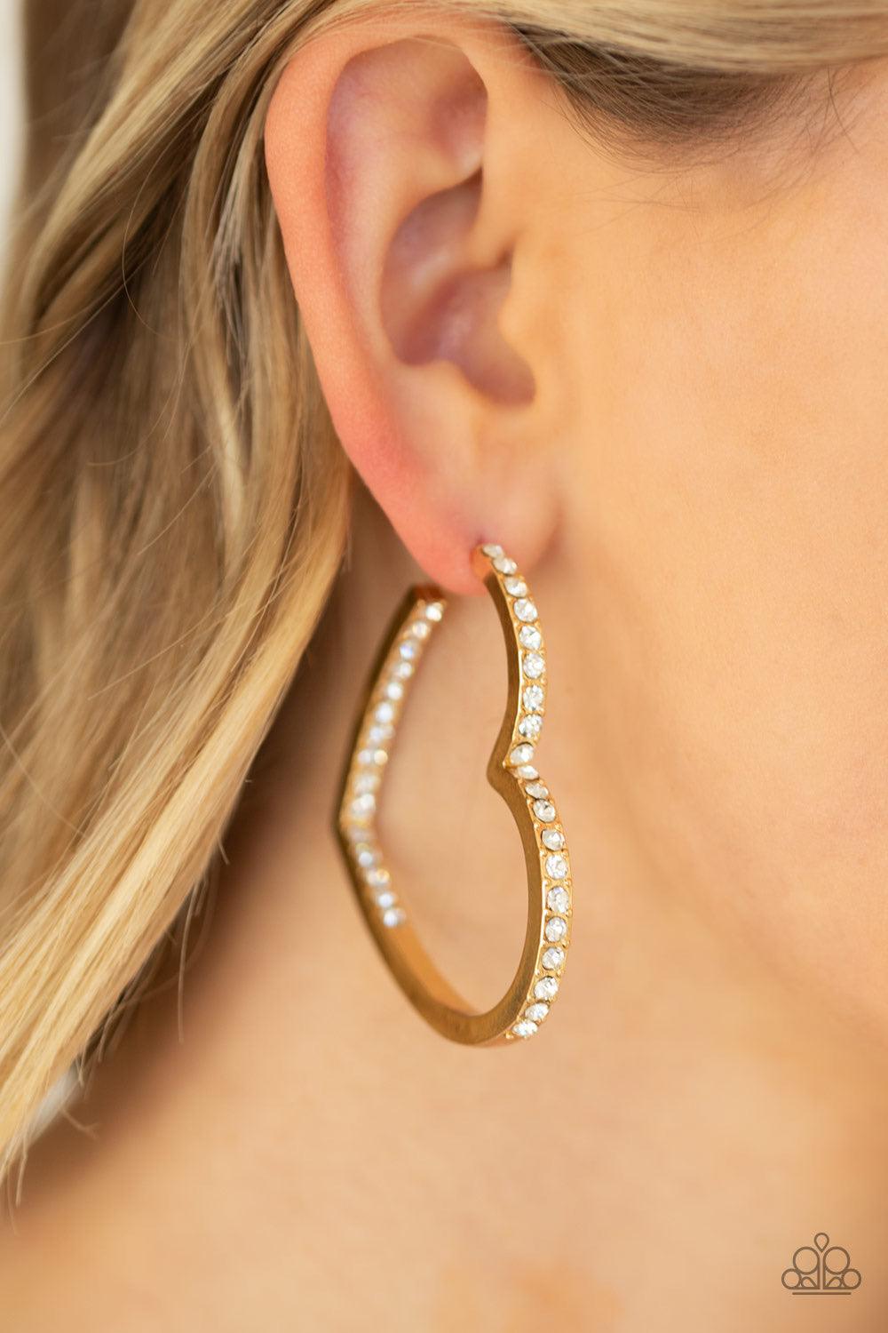 Paparazzi Accessories Heartbreaker - Gold Encrusted in sections of glittery white rhinestones, a glistening gold hoop curls into a charming heart shape for a heart-stopping look. Earring attaches to a standard post fitting. Hoop measures approximately 2"