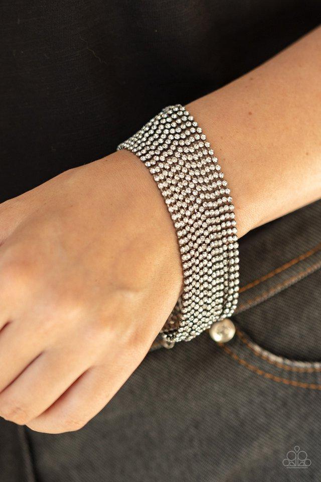 Paparazzi Accessories I Woke Up Like This - Black Strung between two gunmetal fittings, sparkly strand after sparkly strand of glittery white rhinestones layer around the wrist, creating a glamorous statement piece. Features an adjustable clasp closure. J
