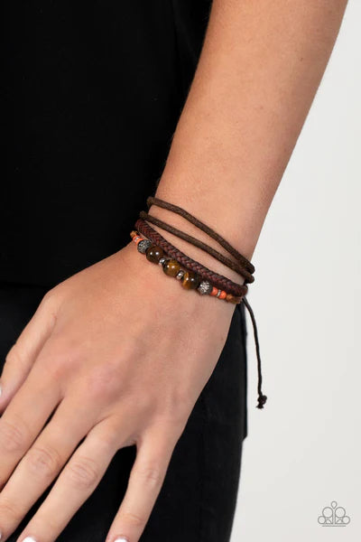 Paparazzi Accessories Tundra Tracker - Orange A strand of tiger's eye stones, orange accents, and decorative silver beads join layers of mismatched leather bands around the wrist for a groovy grounding effect. Features an adjustable sliding knot closure.
