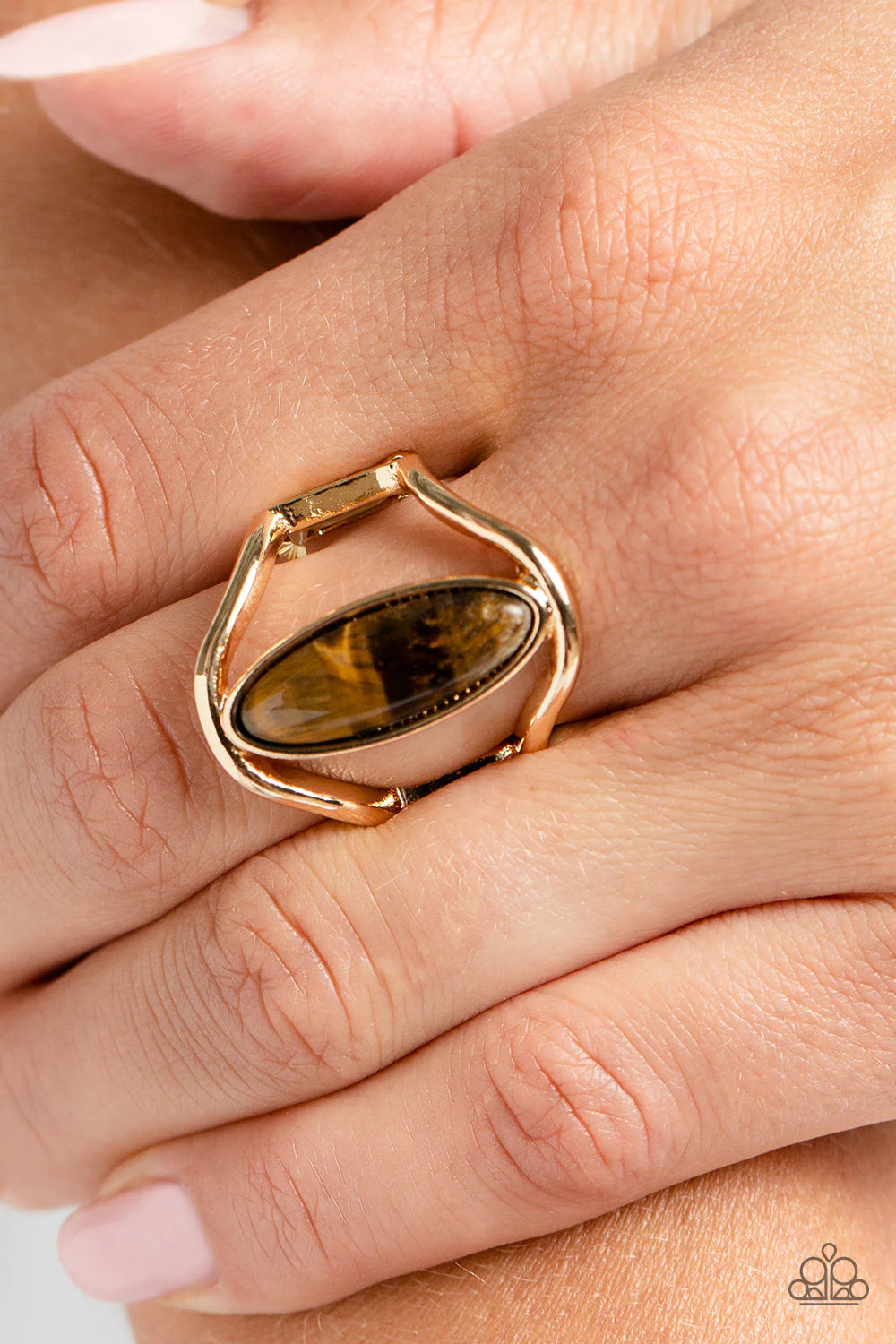 Paparazzi Accessories Spartan Stone - Brown An elongated tiger's eye oval stone sits between two shiny gold bands that arc around it, creating the illusion of a floating southwestern centerpiece. Features a stretchy band for a flexible fit. As the stone e