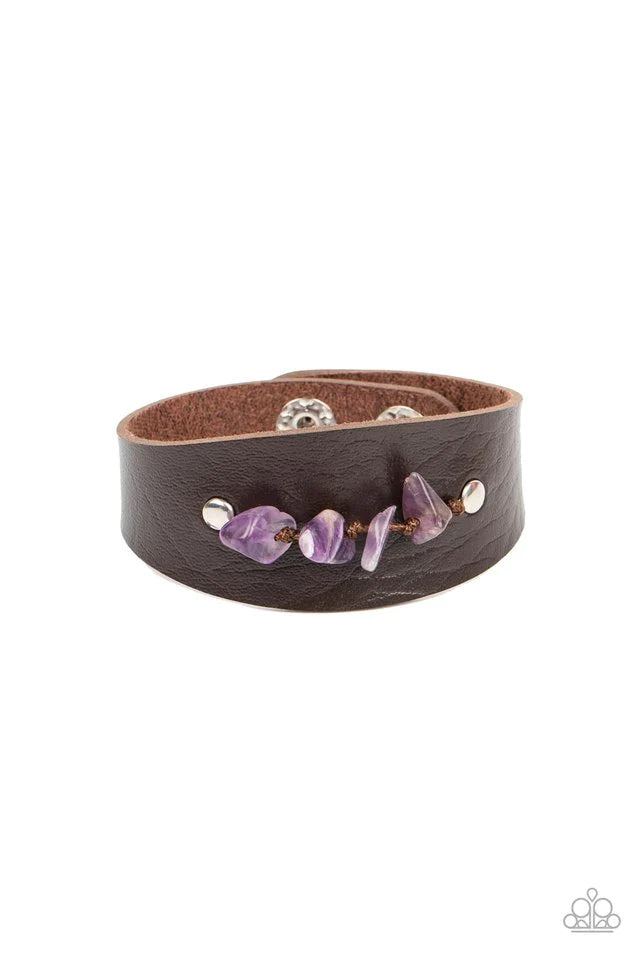 Paparazzi Accessories Colorful Canyoneer - Purple Pieces of amethyst pebbles are threaded along a brown cord that is studded in place across the front of a rounded leather band, resulting in an earthy pop of color atop the wrist. Features an adjustable sn