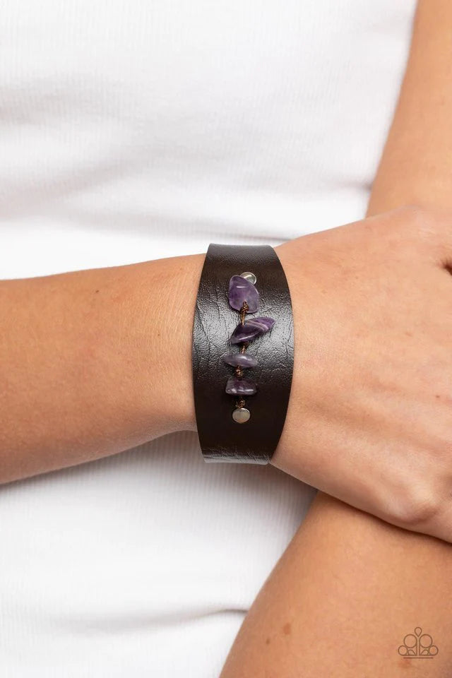 Paparazzi Accessories Colorful Canyoneer - Purple Pieces of amethyst pebbles are threaded along a brown cord that is studded in place across the front of a rounded leather band, resulting in an earthy pop of color atop the wrist. Features an adjustable sn