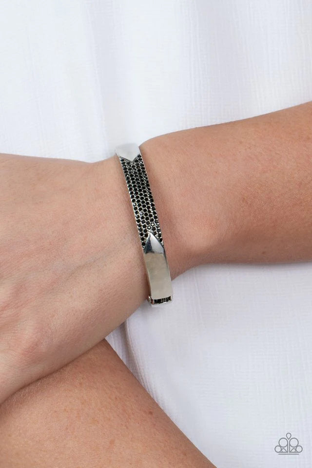 Paparazzi Accessories Radiant Edge - Black Rows of glittery black rhinestones stack horizontally across the center of a silver bangle-like bracelet, creating a sparkly geometric accent around the wrist. Features a hinged closure. Jewelry