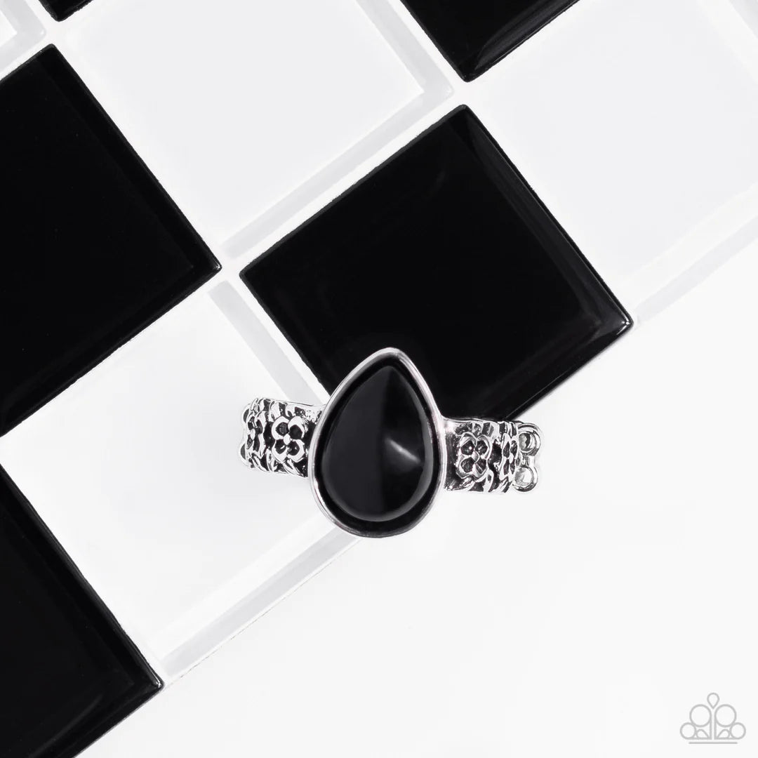 Paparazzi Accessories Rainbow Raindrops - Black A polished teardrop-shaped bead in a black shade is wrapped in a silver frame and set atop a silver band. Floral details embellish the band on each side of the centerpiece, adding a touch of charm as it wrap
