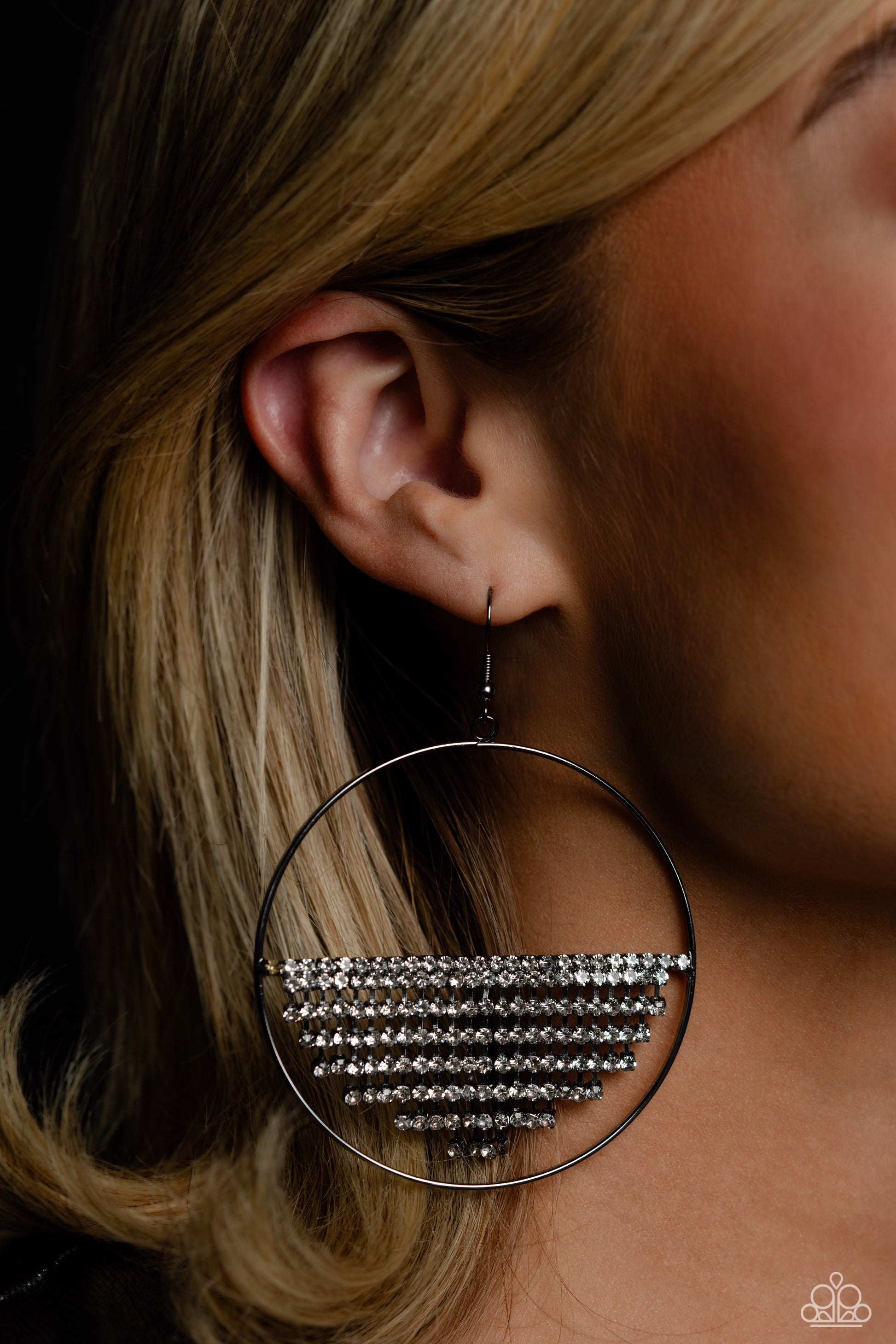Paparazzi Accessories Fierce Fringe - Black A curtain of white rhinestones is stretched between the edges of a skinny, oversized gunmetal hoop, creating a shimmering display. The rhinestones taper towards the center as they sway and cascade, adding sparkl