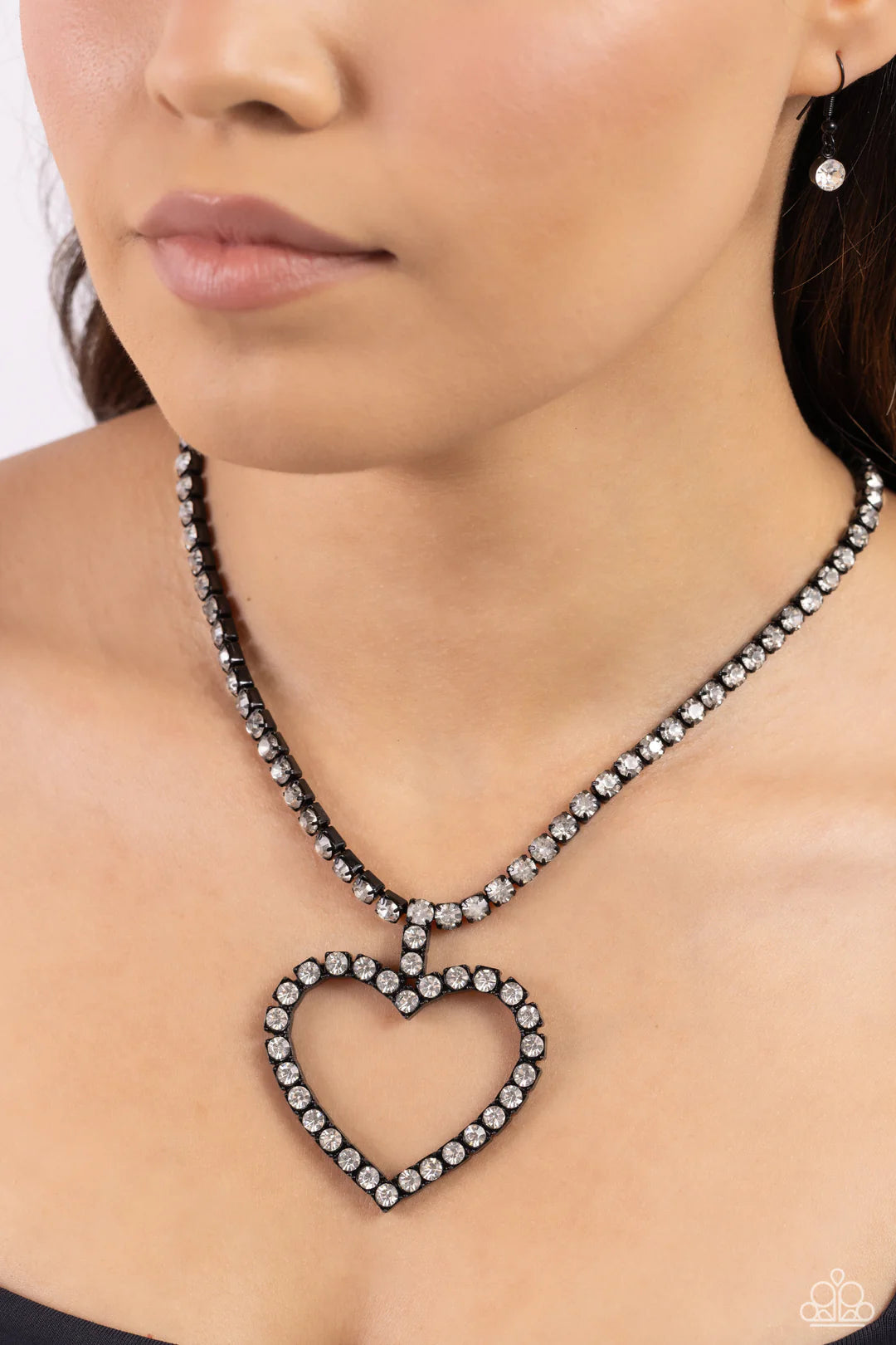Paparazzi Accessories Flirting Fancy - Black Featuring pronged, square black fittings, glassy white rhinestones encircle the neckline and lead the eye down to an airy heart silhouette, resulting in a flirtatious sparkle. Features an adjustable clasp closu