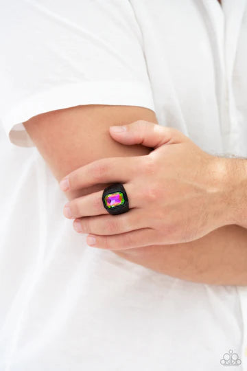 Paparazzi Accessories Cavalier Claim - Multi Featuring a regal emerald style cut, a glittery oil spill gem is pressed into a sleek black frame featuring a thick black band embossed in bold textures. Features a stretchy band for a flexible fit. Sold as one