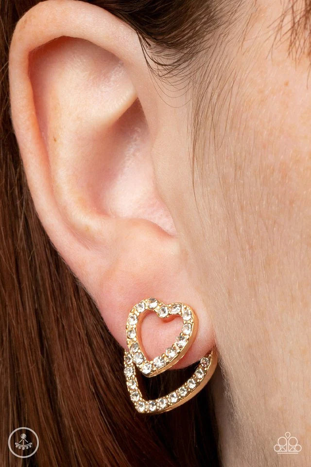 Paparazzi Accessories Ever Enamored - Gold A dainty gold heart dotted in glassy white rhinestones flirtatiously attaches to a double-sided post, while a slightly larger white rhinestone encrusted gold heart peeks out beneath the ear for a romantic finish.