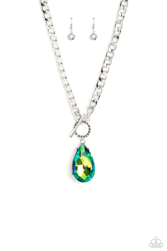 Paparazzi Accessories Edgy Exaggeration - Green Featuring an elegant lariat closure, an oversized, faceted, stellar green UV shimmery teardrop gem, encased in an elevated pronged silver frame cascades from the bottom of a silver curb chain in a whimsical