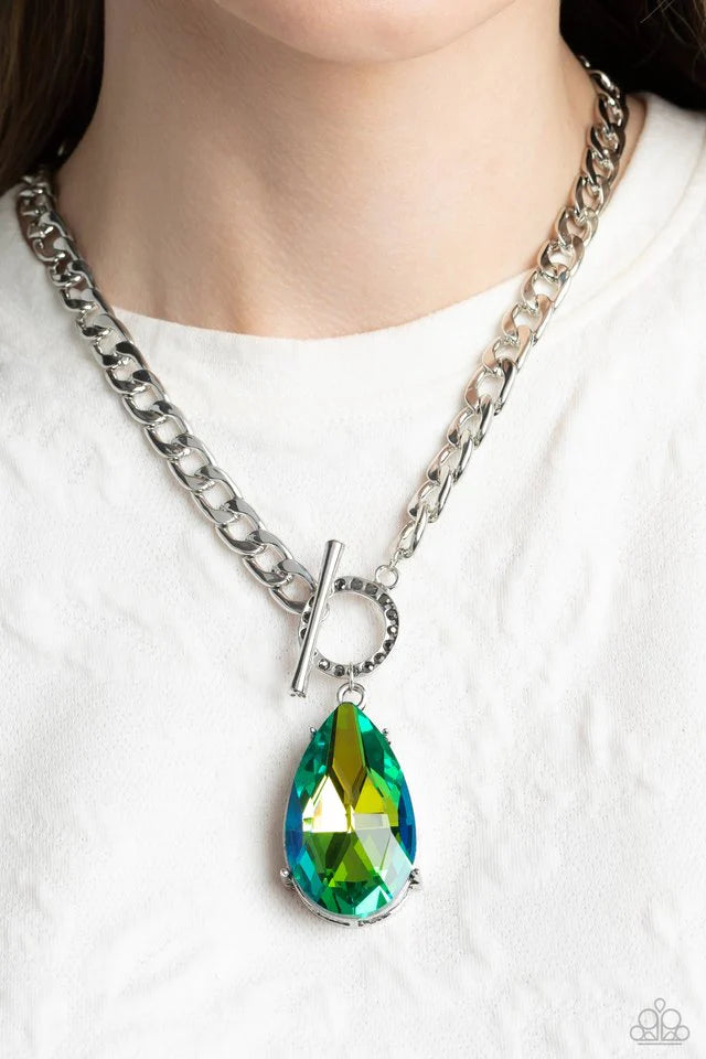 Paparazzi Accessories Edgy Exaggeration - Green Featuring an elegant lariat closure, an oversized, faceted, stellar green UV shimmery teardrop gem, encased in an elevated pronged silver frame cascades from the bottom of a silver curb chain in a whimsical
