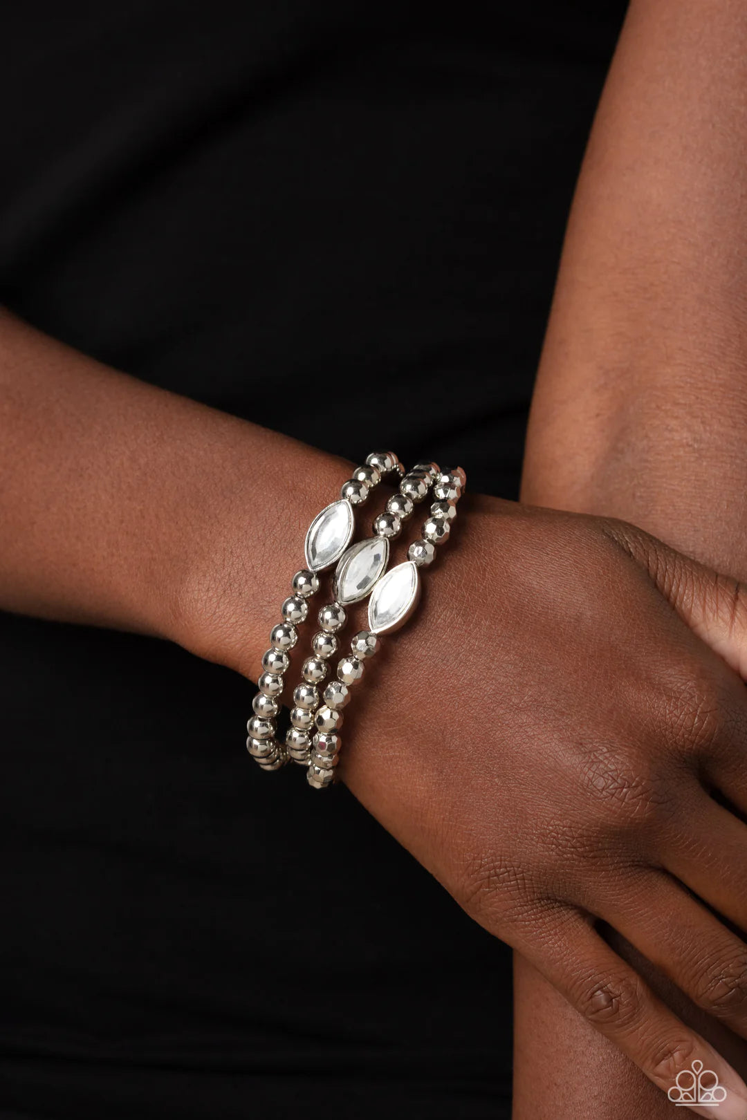 Paparazzi Accessories Twinkling Team - White Featured in the center of a faceted and smooth silver beaded display, a dazzling white, marquise-cut gem pressed in a sleek silver frame wraps around the wrist on elastic stretchy bands for a classy statement.