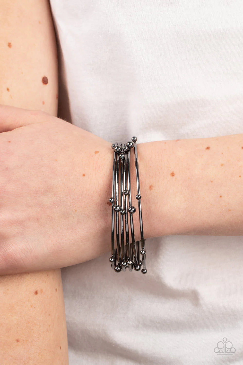 Paparazzi Accessories Metro Satellite - Black Haphazardly dotted with gunmetal studs of varying sizes, a glistening stack of gunmetal bangles glides along the wrist for a noise-making shimmer. Sold as one set of six bracelets. Jewelry