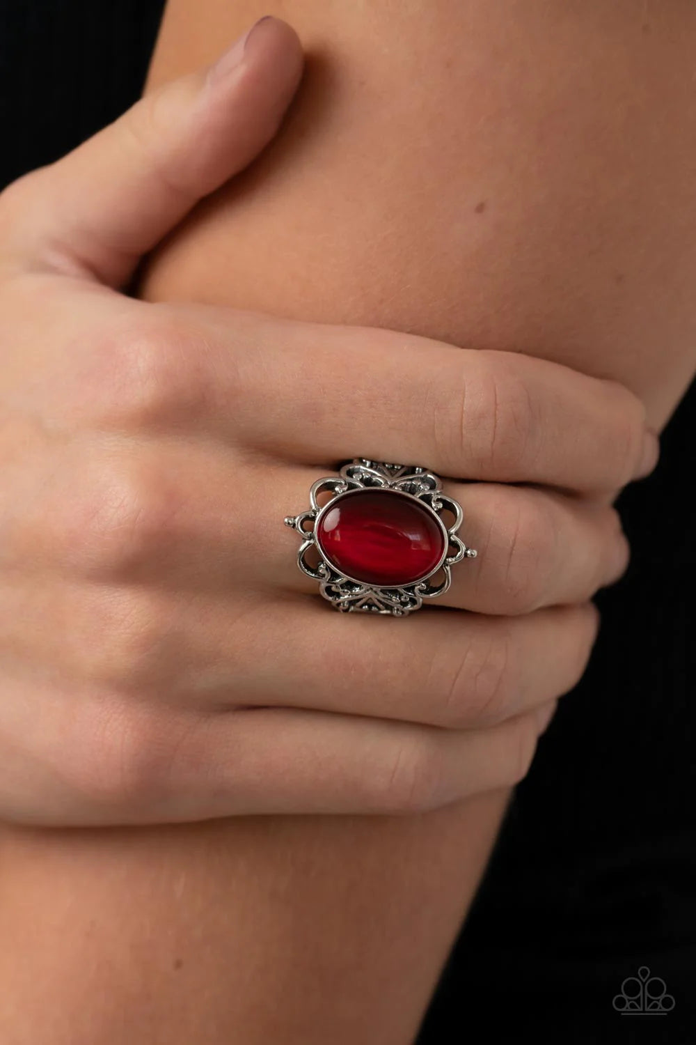 Paparazzi Accessories Radiantly Reminiscent - Red An oversized oval Fire Whirl cat's eye stone is pressed into a frilly silver backdrop whirling with studded filigree, resulting in a whimsical glow atop the finger. Features a stretchy band for a flexible