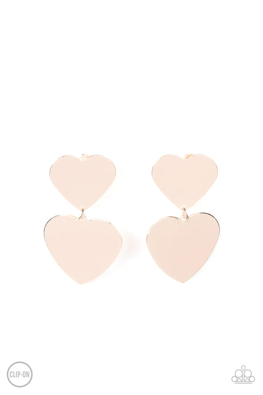 Paparazzi Accessories Cowgirl Crush - Rose Gold *Clip-On Featuring a shimmery scratched finish, an oversized rose gold heart charm swings from the bottom of a smaller rose gold heart charm, resulting in a flirtatious lure. Earring attaches to a standard c