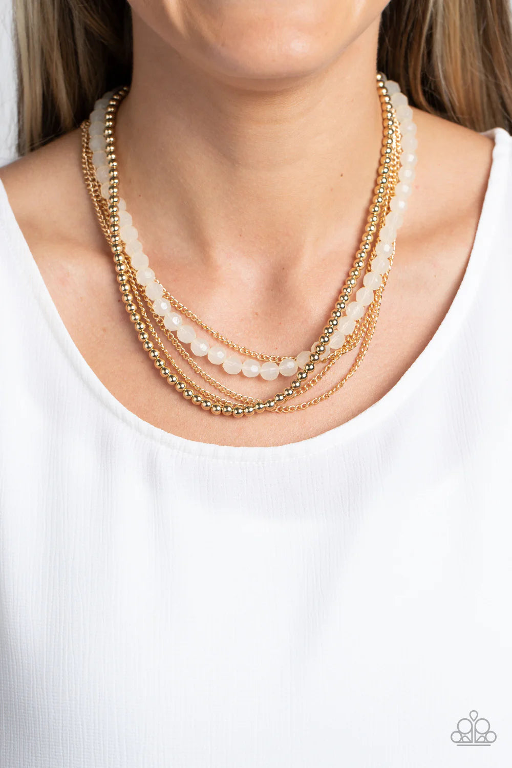 Paparazzi Accessories Boardwalk Babe - Gold Shiny gold beads fall together with classic gold chains to create shimmery layers along the collar. A strand of opaque, faceted beads, in the calming shade of ivory, emerges from the backdrop of metallic sheen,