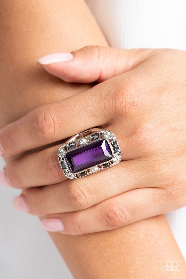 Paparazzi Accessories Radiant Rhinestones - Purple Pressed into a curved, rectangular silver frame, an oversized emerald-cut purple gem shines atop the finger. Dainty square and round gems in shades of white and smoky black airily encircle the oversized g